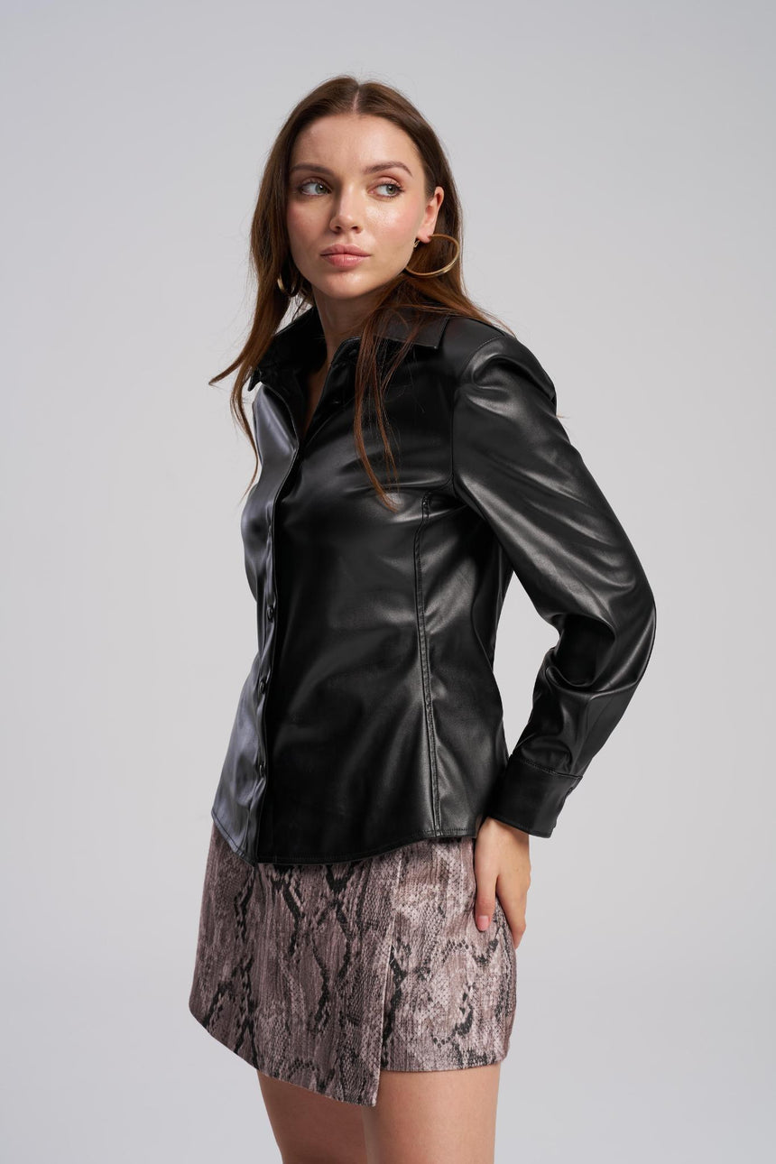 Woman wearing a black leather jacket and patterned skirt on a gray background
