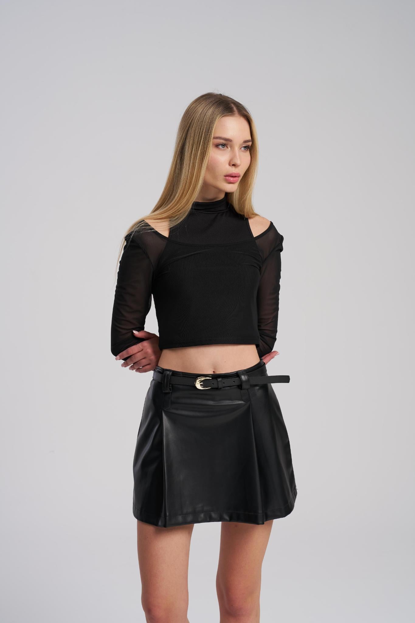 Woman wearing a black mesh top and leather skirt on a gray background
