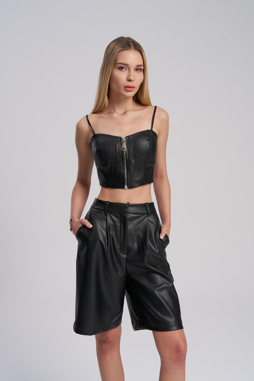 Woman wearing a black leather top and shorts on a gray background