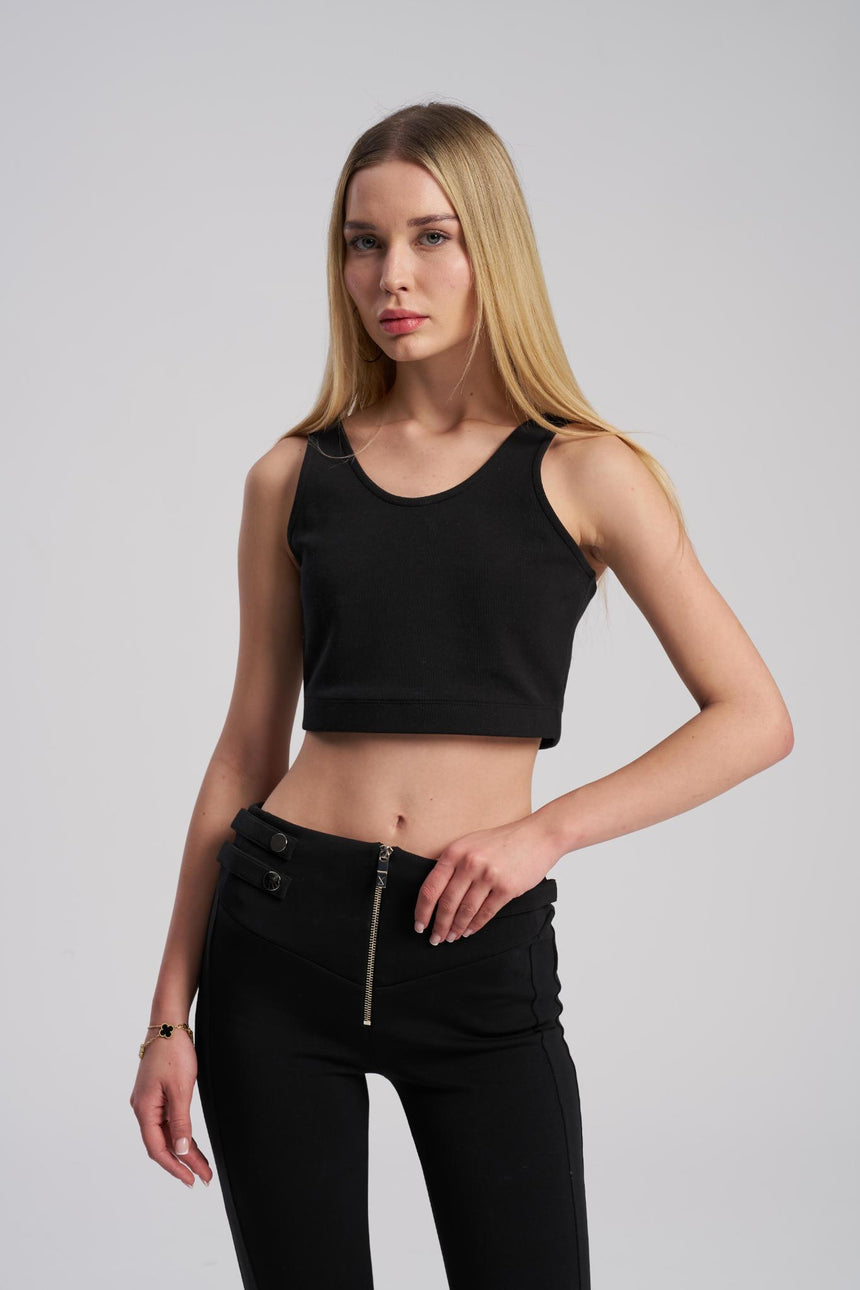 Woman wearing a black sleeveless top and black pants on a gray background