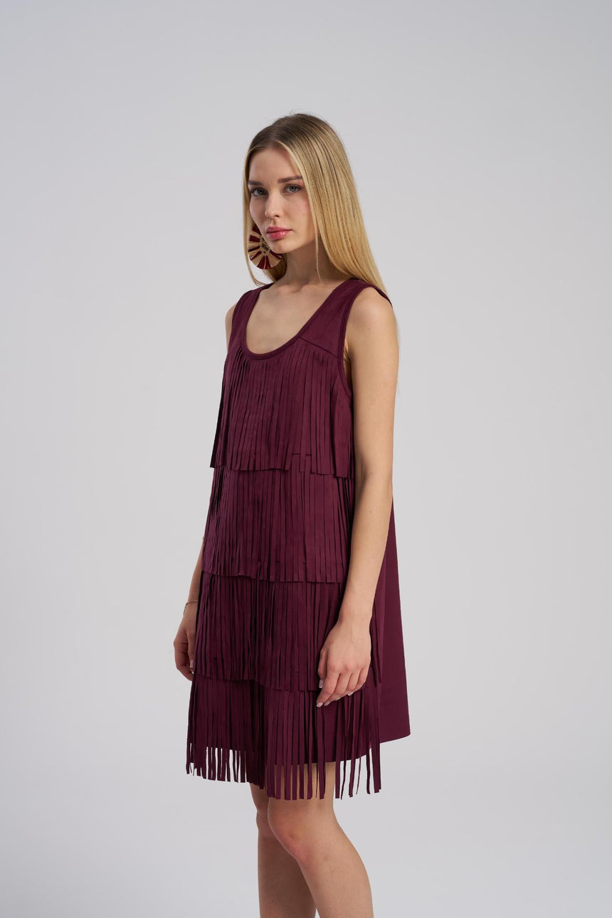 Woman wearing a burgundy fringe dress against a white background