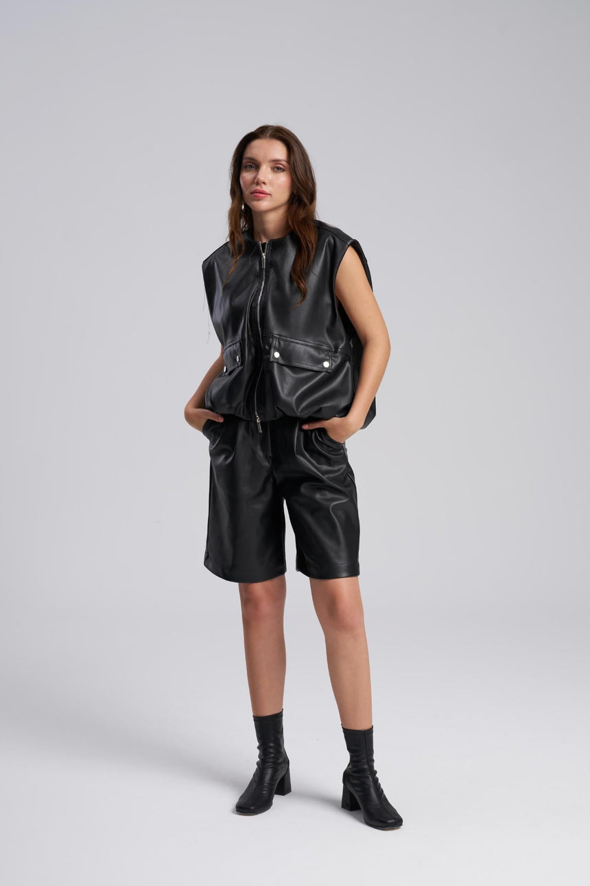 Person wearing a black leather vest and shorts on a white background