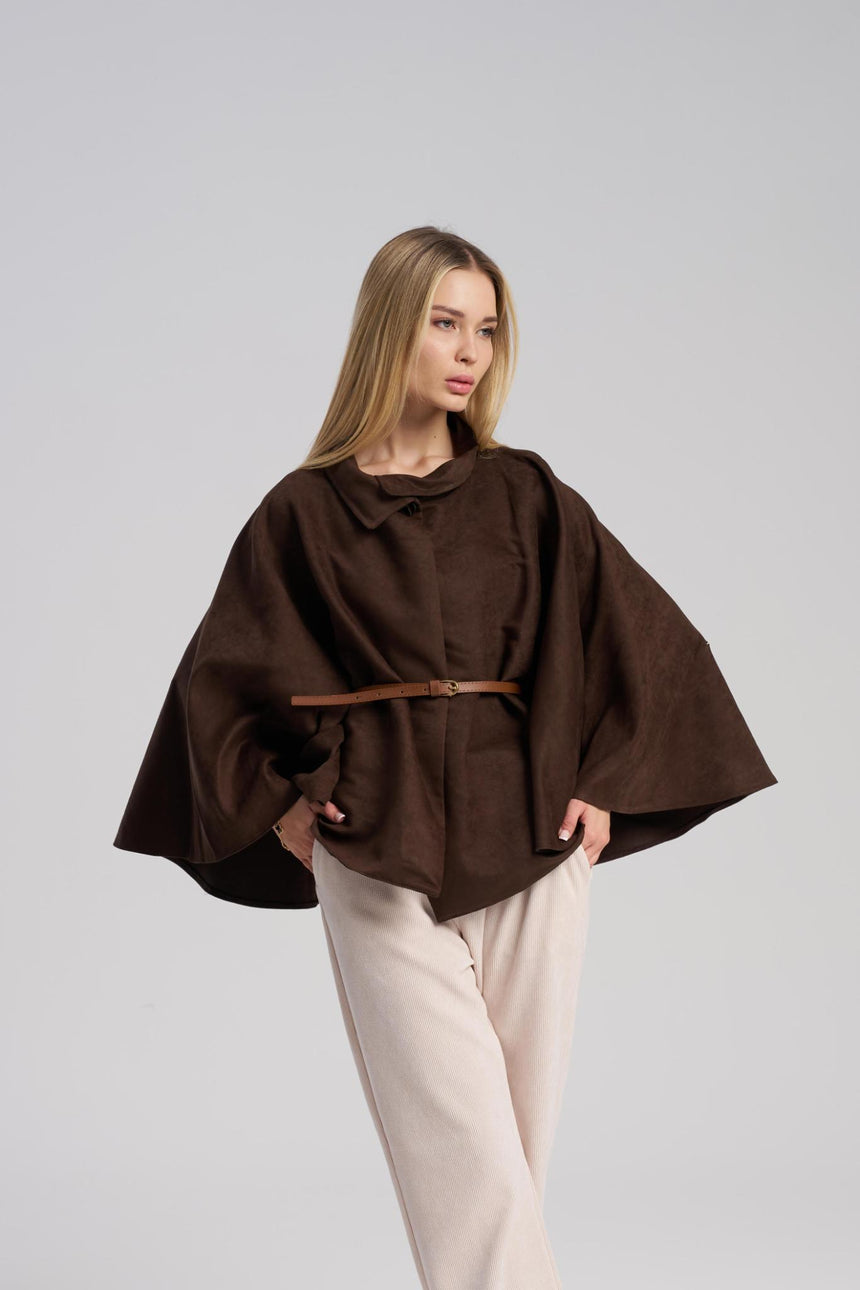 Woman wearing a brown poncho with a belt on a gray background