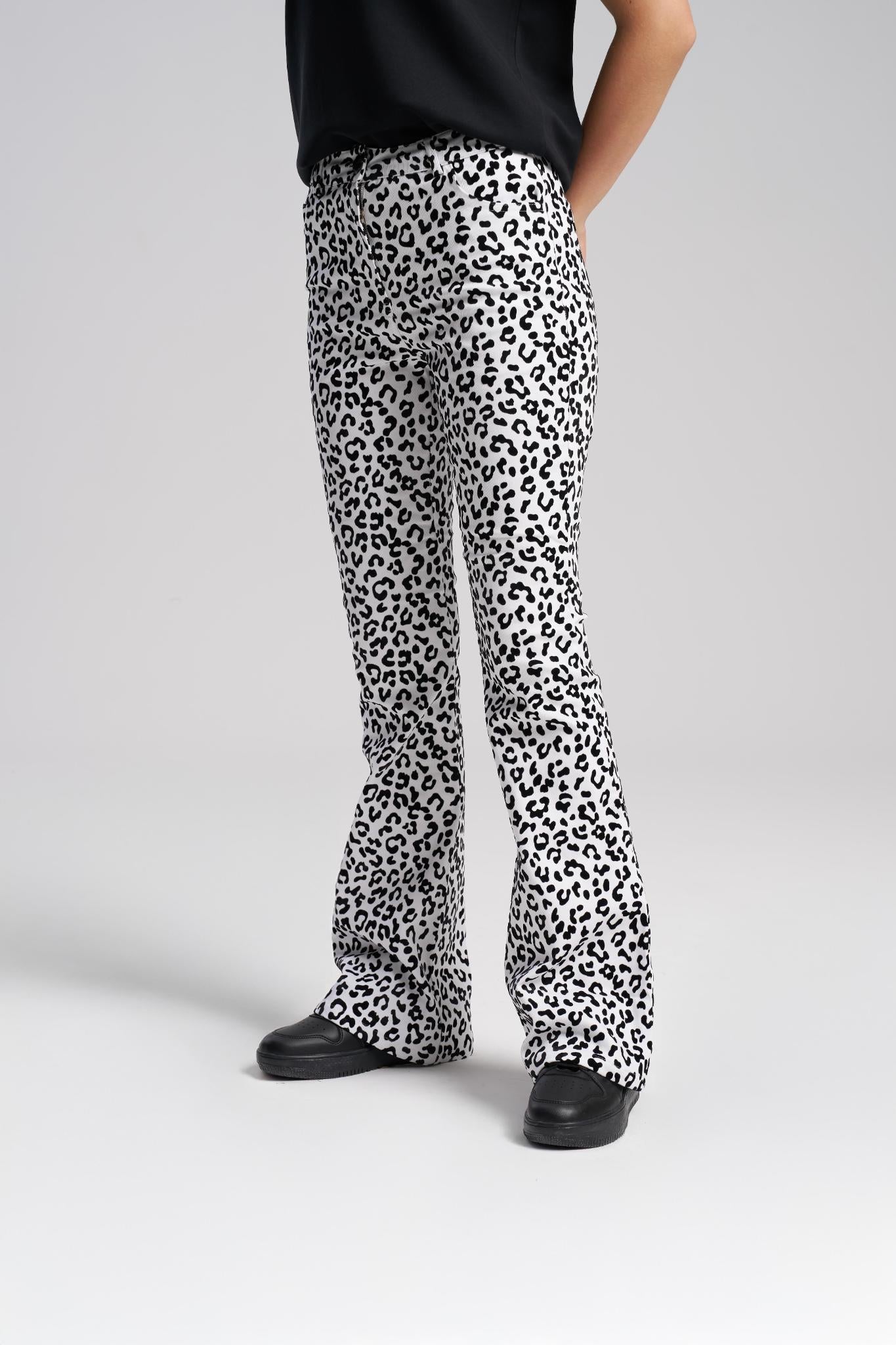Person wearing leopard print pants on a plain background