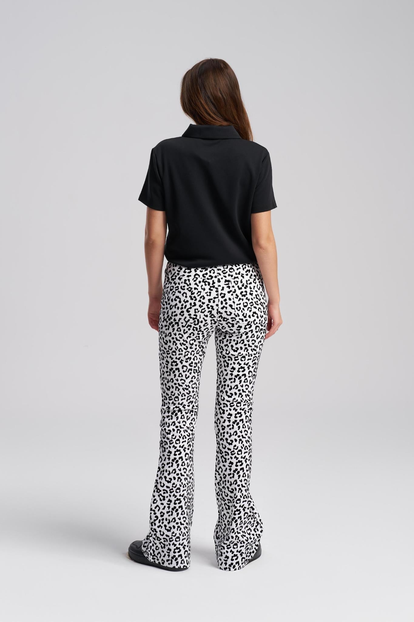 Person wearing a black polo shirt and leopard print pants on a white background