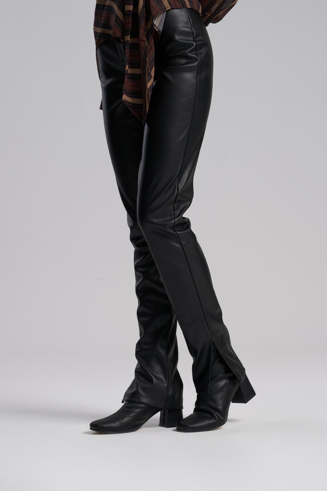 Person wearing black leather pants and boots on a plain background