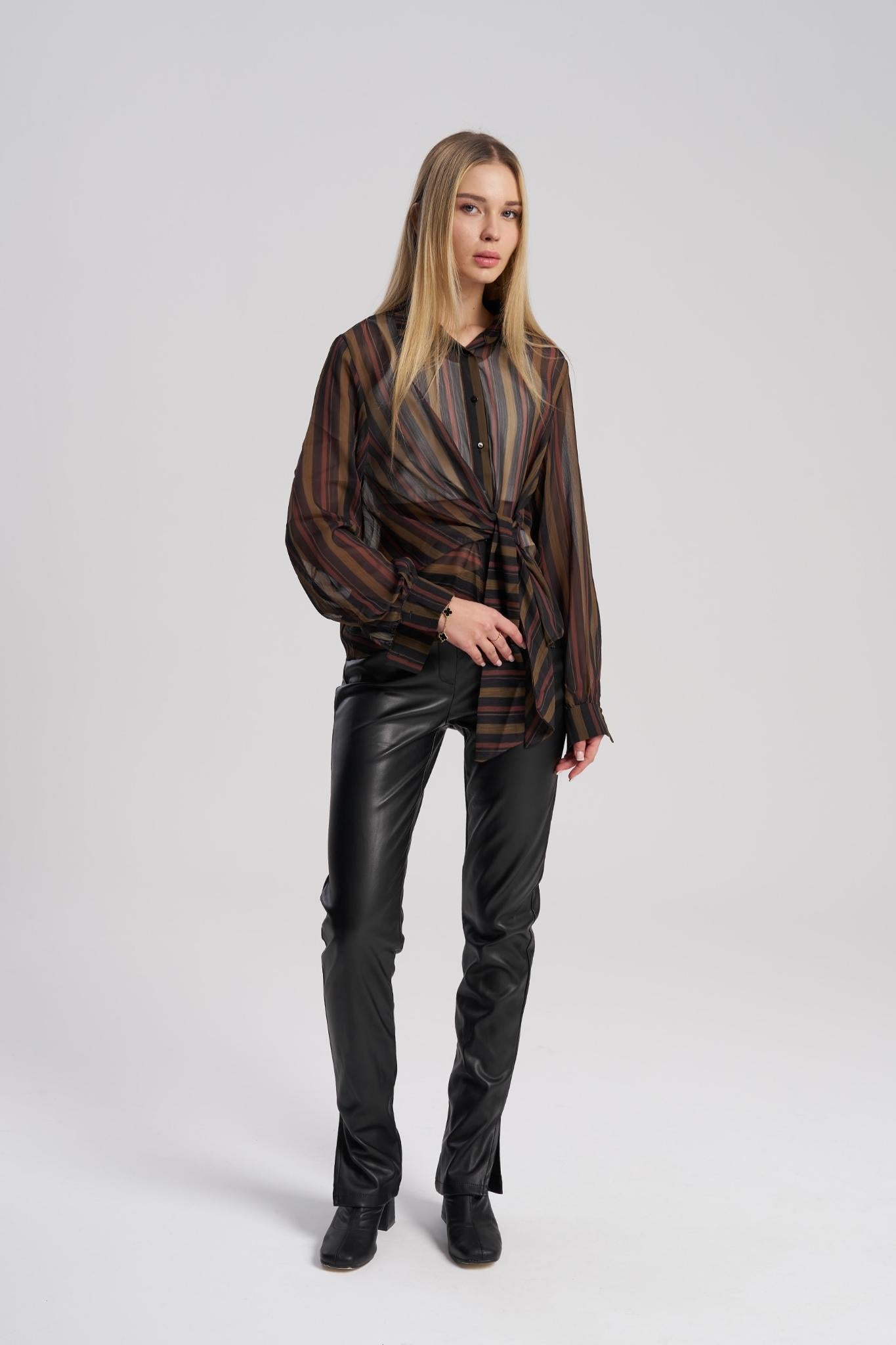 Woman wearing a striped shirt and black leather pants on a white background