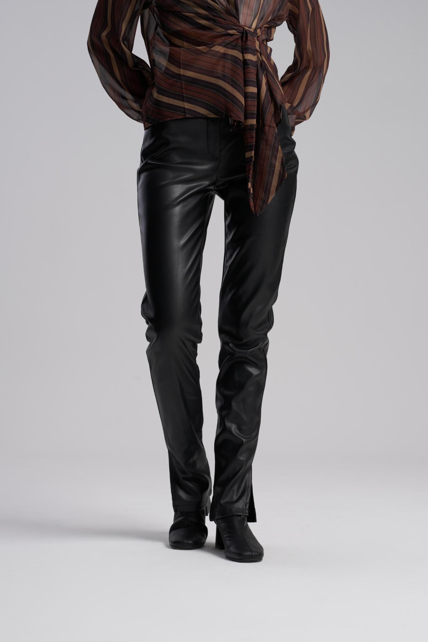 Person wearing a brown patterned shirt and black leather pants on a gray background