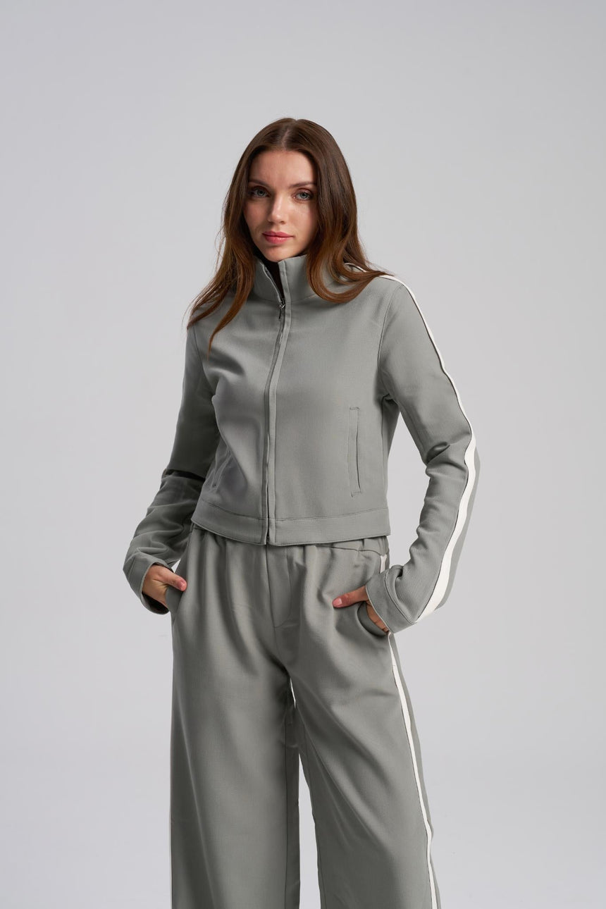 Woman wearing a tracksuit with a white stripe on a light gray background