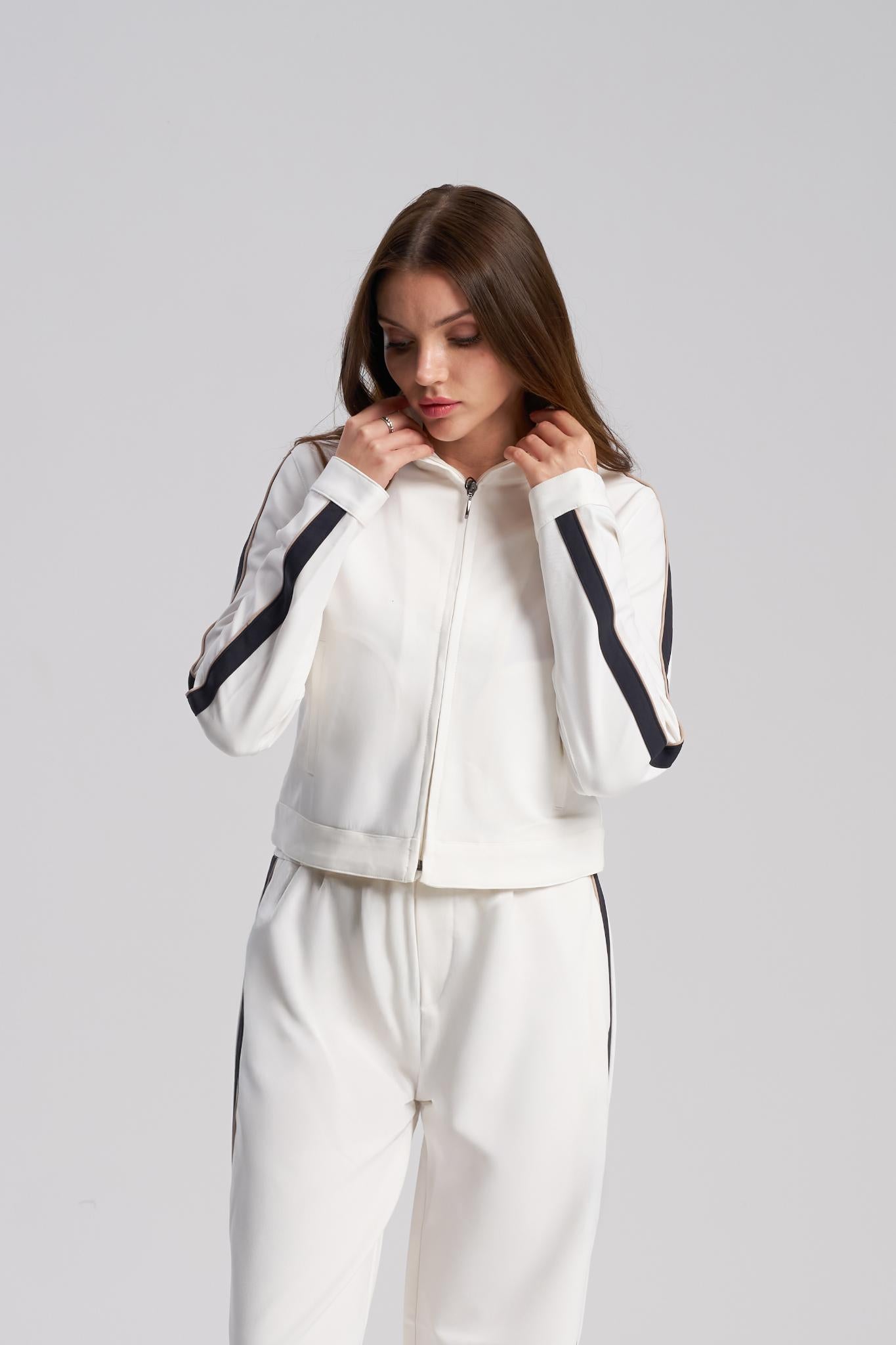 Woman wearing a white tracksuit with black accents on a gray background