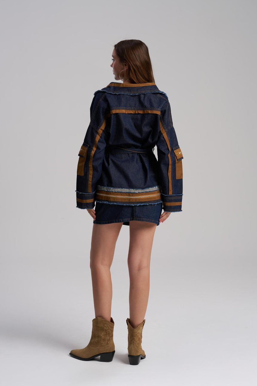Woman wearing a navy jacket with brown accents and matching mini skirt on a white background