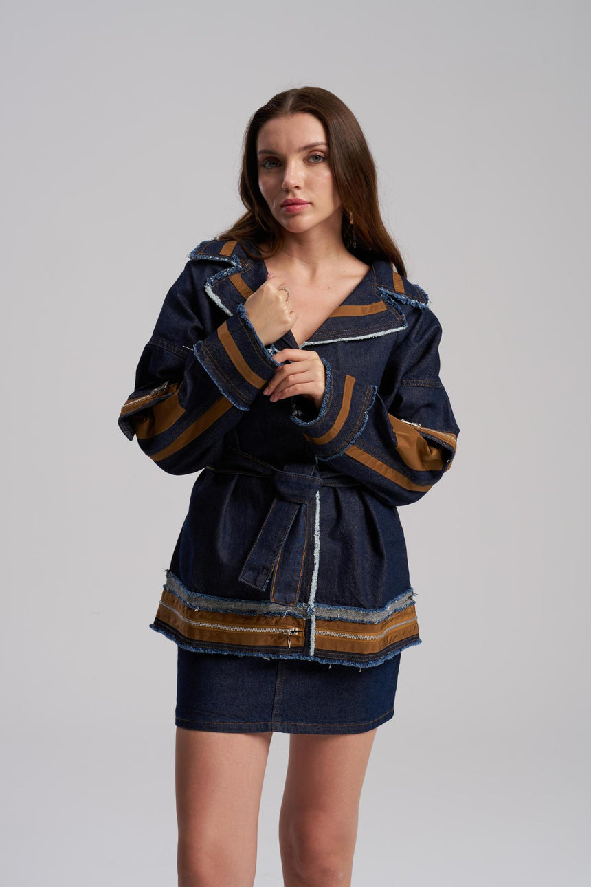 Woman wearing a dark blue jacket with brown accents on a gray background