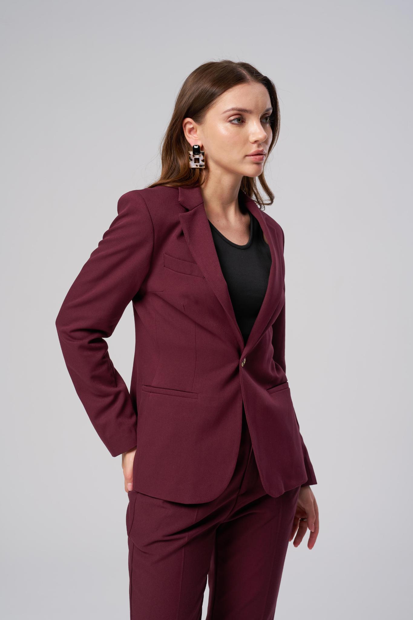 Woman wearing a burgundy work wear suit against a gray background