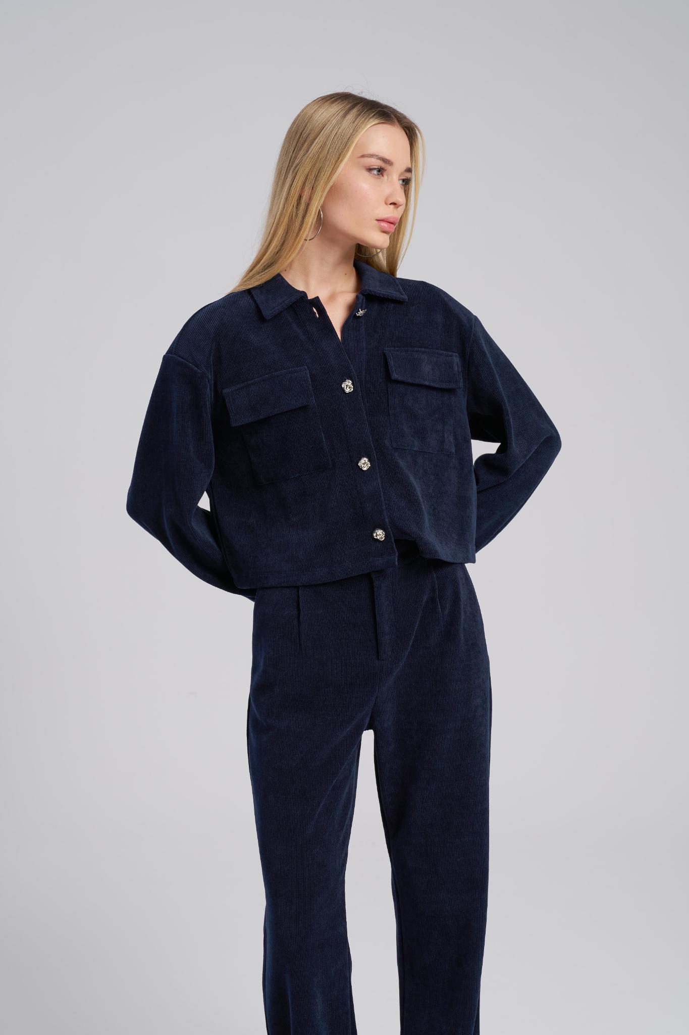 Woman wearing a navy blue corduroy outfit on a gray background