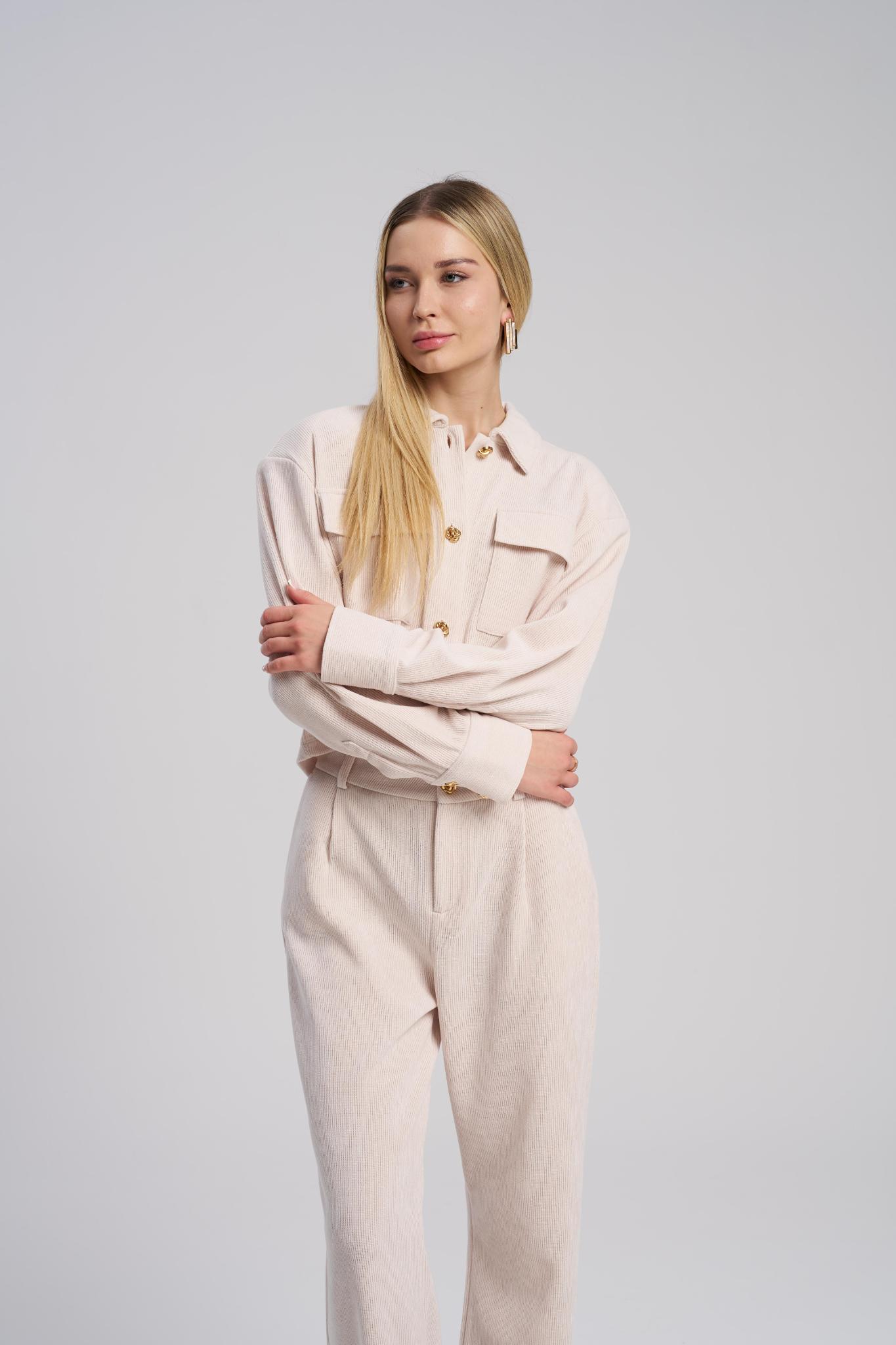 Woman wearing a beige outfit against a plain background
