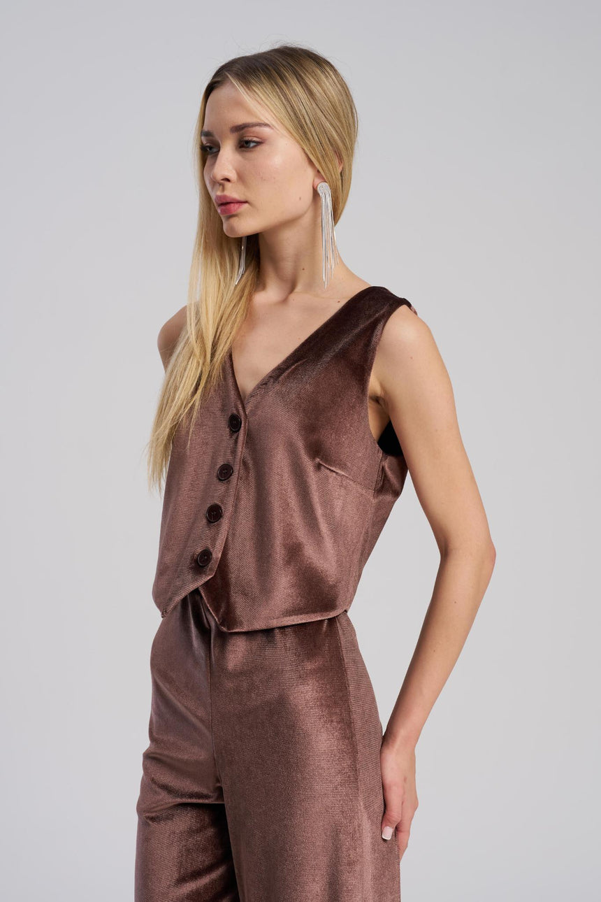 Woman wearing a brown sleeveless top and pants on a gray background