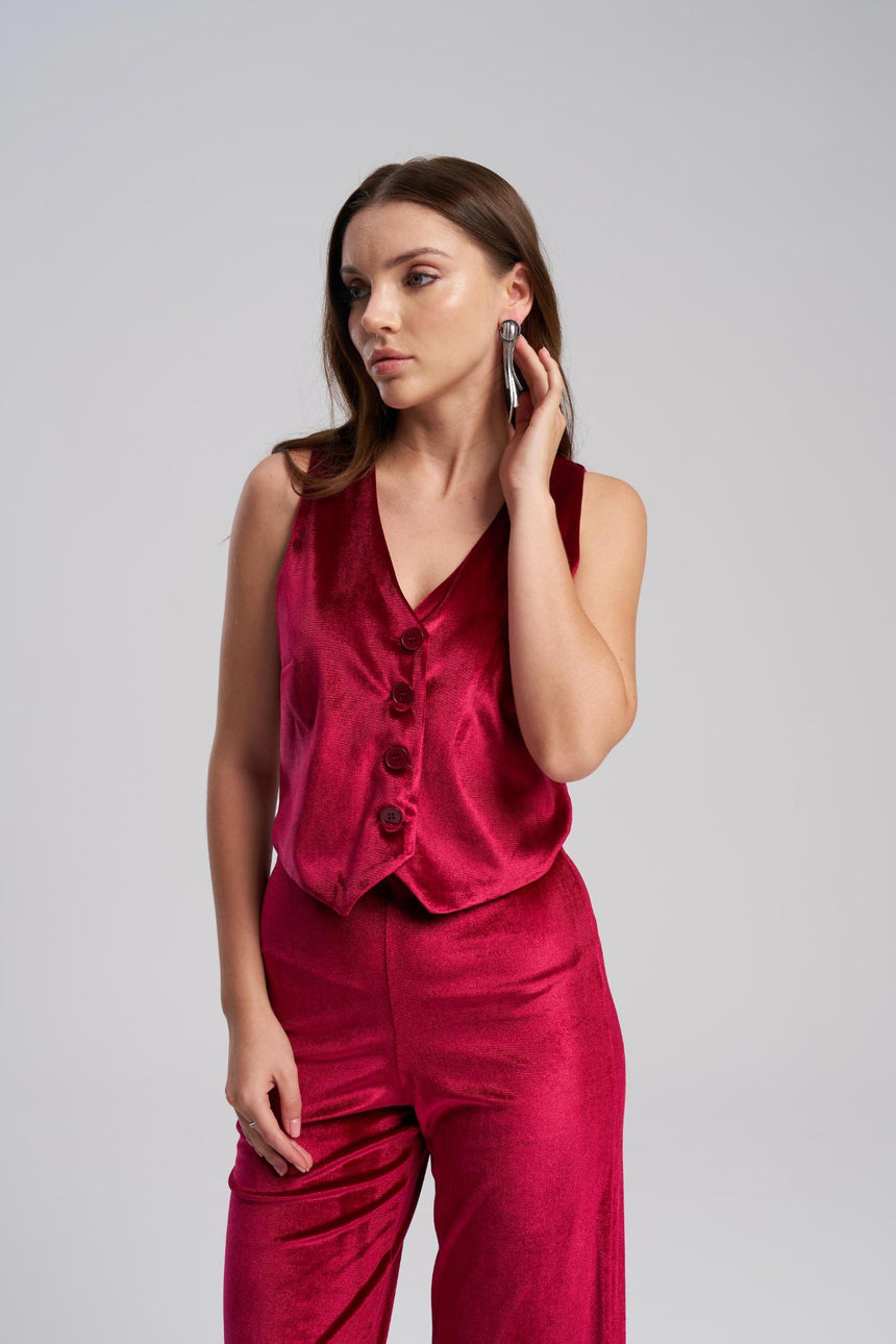 Woman wearing a red outfit with a vest and pants on a gray background