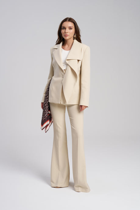 Woman wearing a beige suit with a white top on a gray background