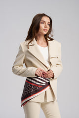 Woman wearing a beige suit with a patterned scarf on a gray background