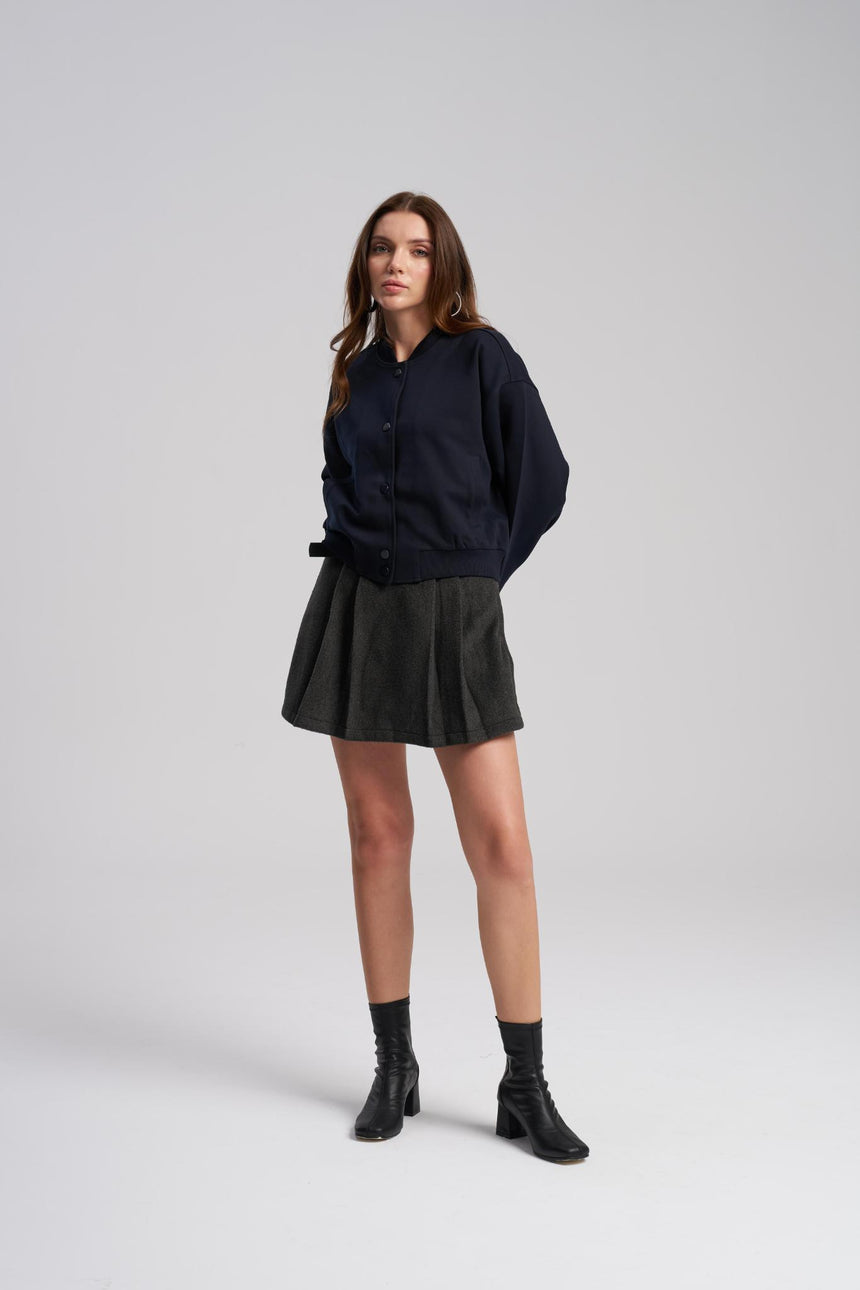 Woman wearing a navy sweater, black skirt, and black boots on a white background