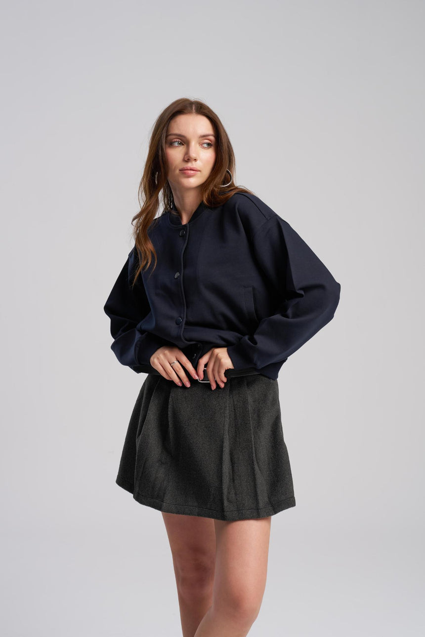 Woman wearing a dark blue oversized shirt and black skirt on a gray background