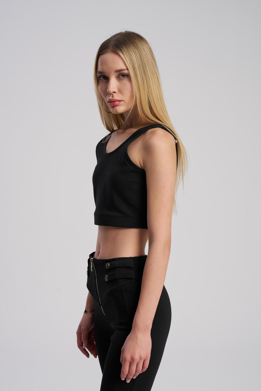 Woman wearing a black crop top and black pants on a light gray background