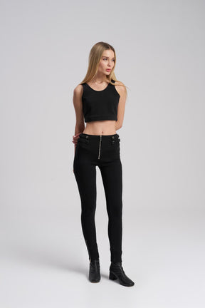 Woman wearing a black crop top and black jeans on a white background