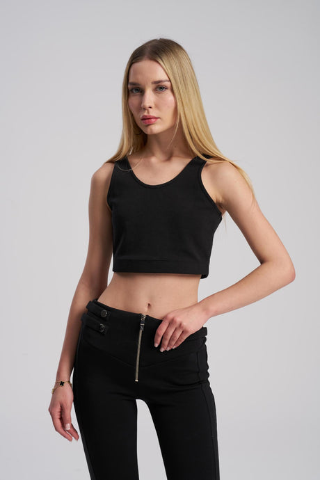 Woman wearing a black sleeveless top and black pants on a gray background