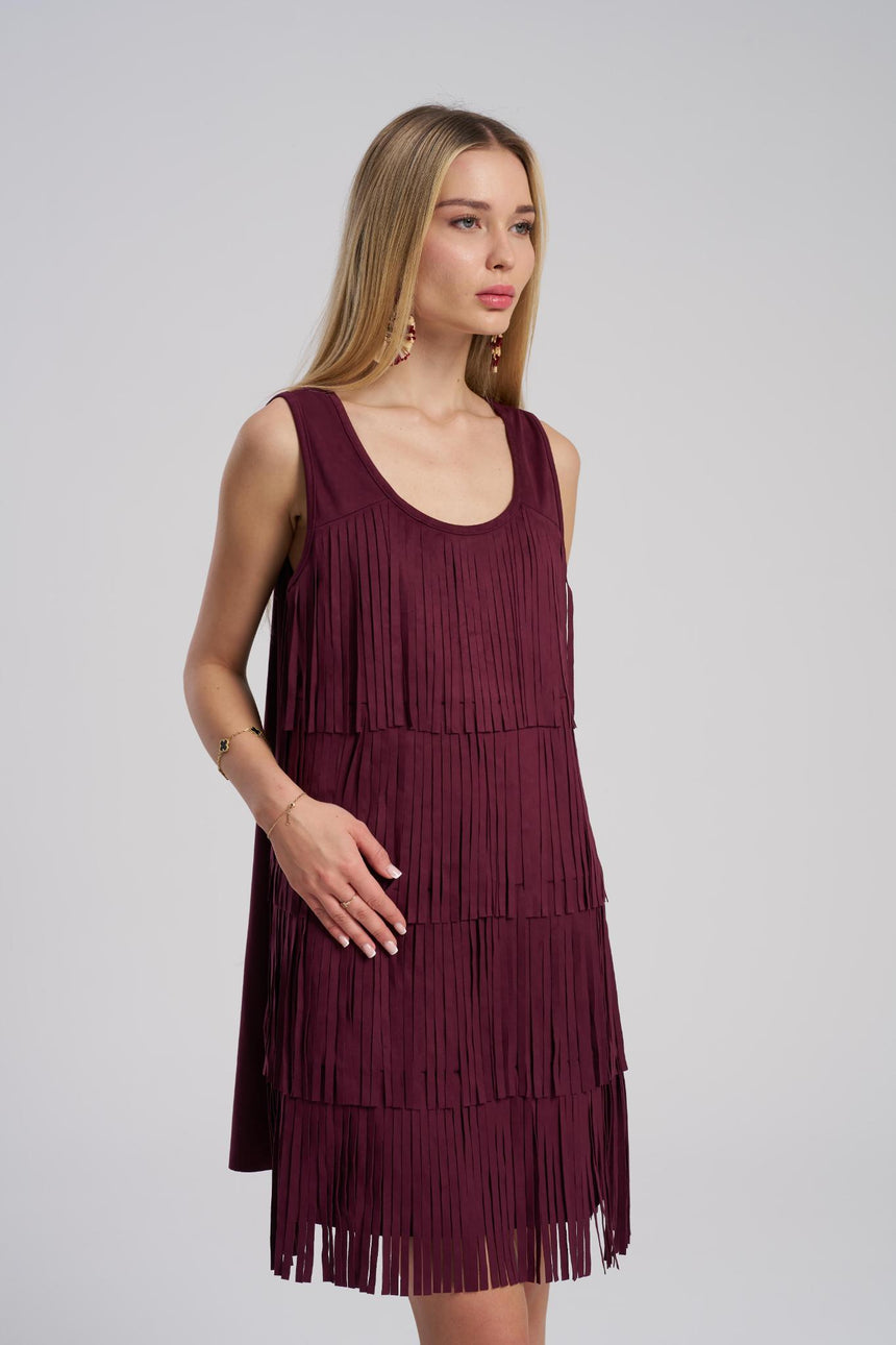 Woman wearing a burgundy fringe dress against a plain background
