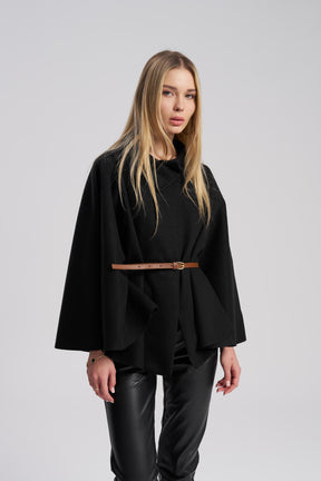 Woman wearing a black Pancho with a brown belt on a gray background