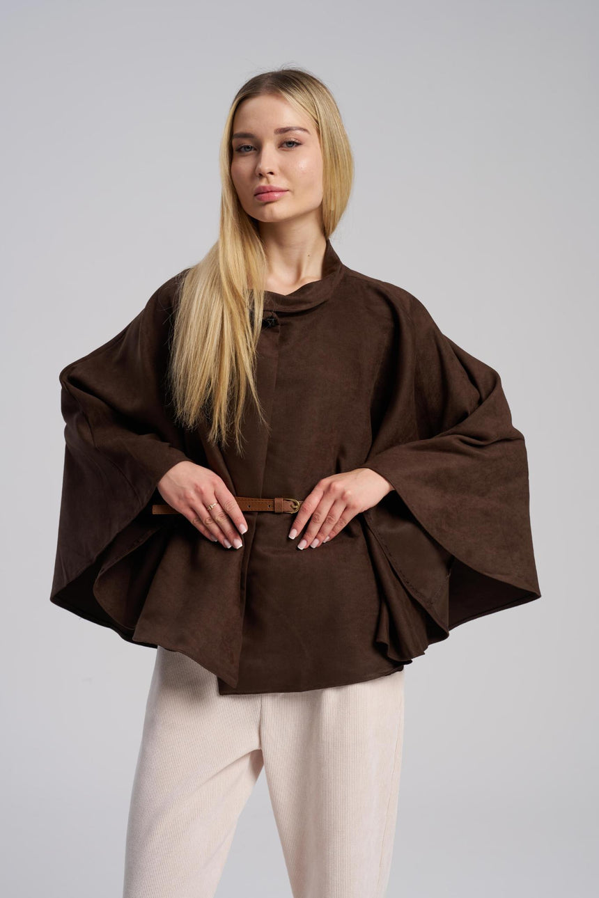 Woman wearing a brown poncho against a plain background