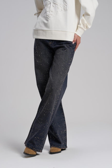 Person wearing dark blue flared jeans and a light-colored hoodie on a plain background
