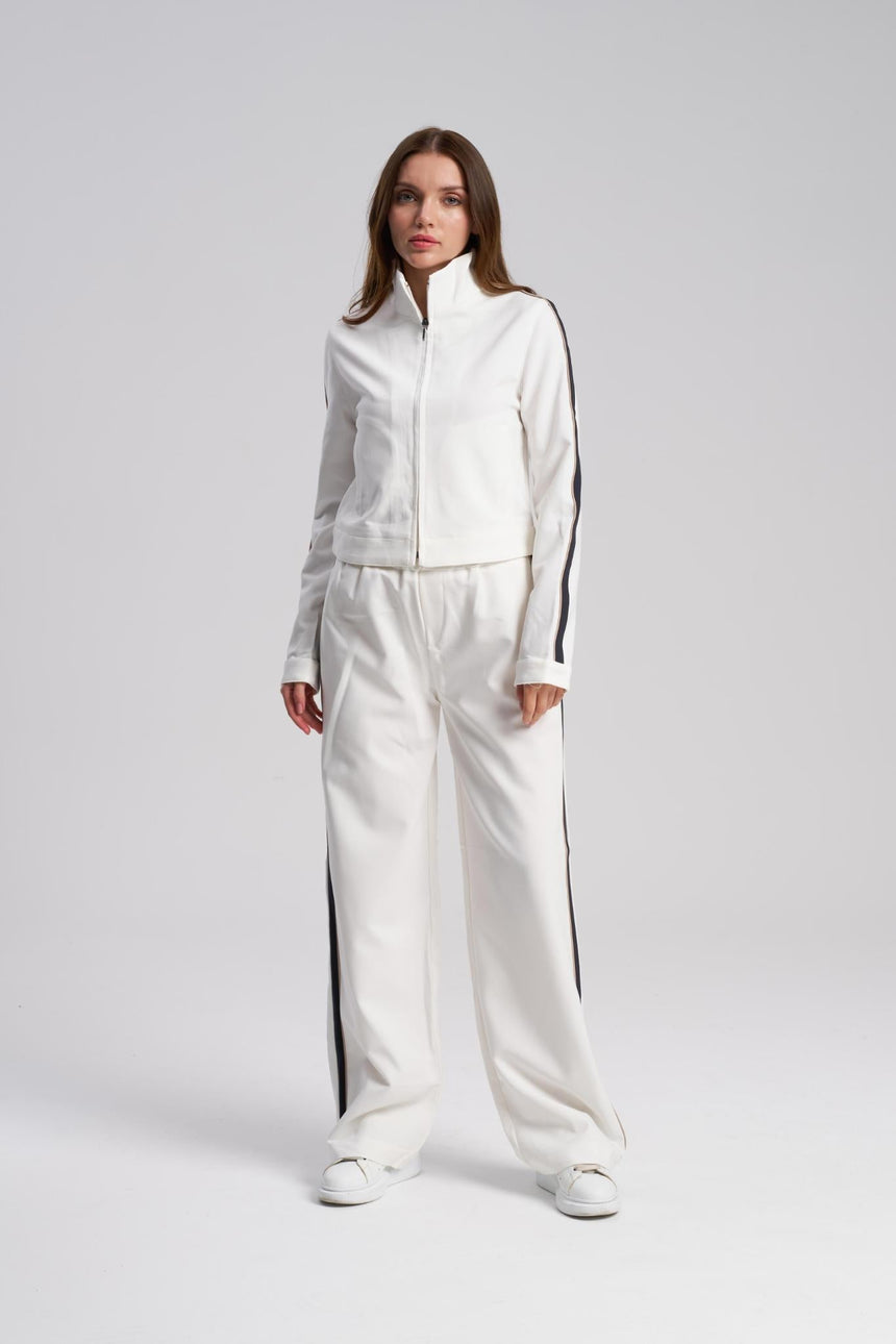 Person wearing a white tracksuit with black stripes on a light gray background