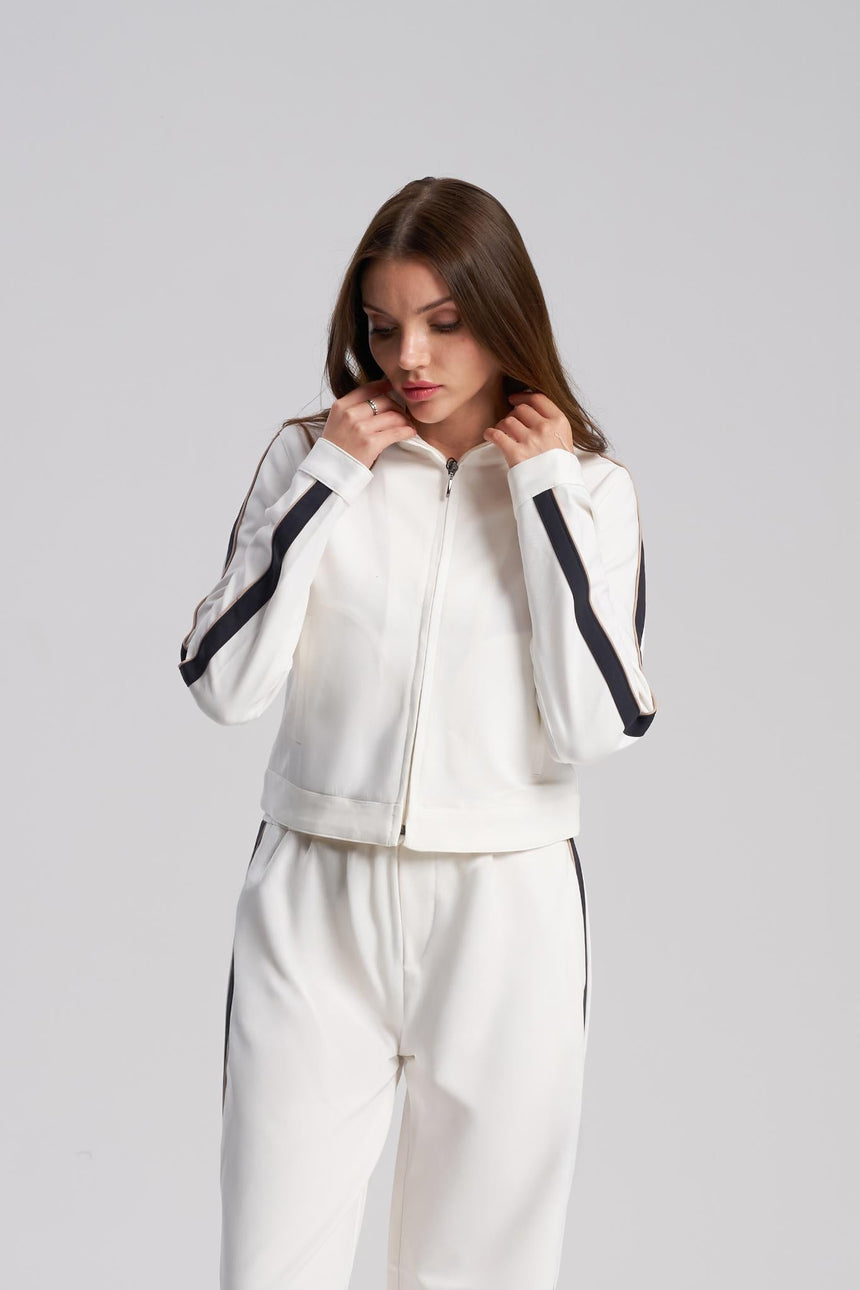 Woman wearing a white tracksuit with black accents on a gray background