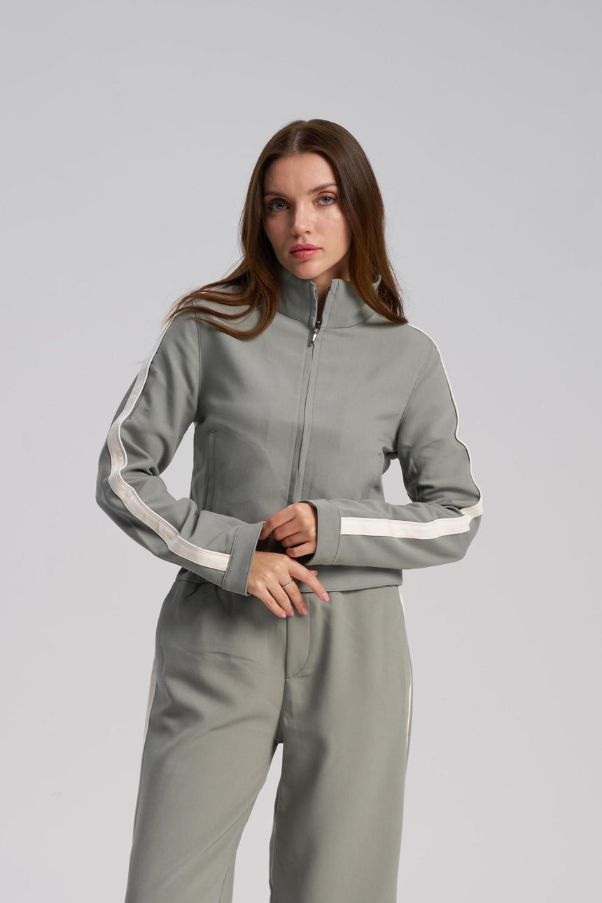Woman wearing a  tracksuit with white stripes on a light gray background