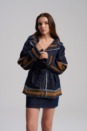 Woman wearing a dark blue jacket with brown accents on a gray background