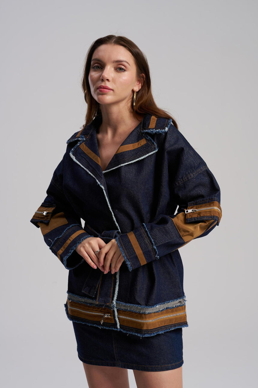 Woman wearing a dark blue jacket with brown accents on a gray background