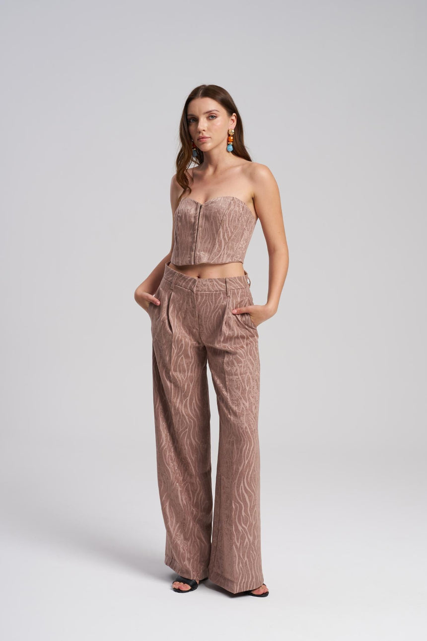 Woman wearing a matching strapless top and wide-leg pants on a white background