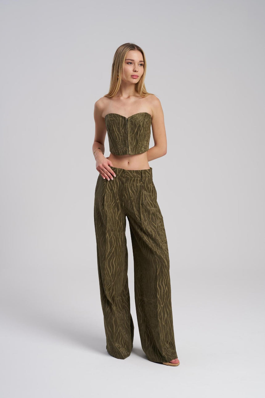 Woman wearing a green strapless top and wide-leg pants on a white background