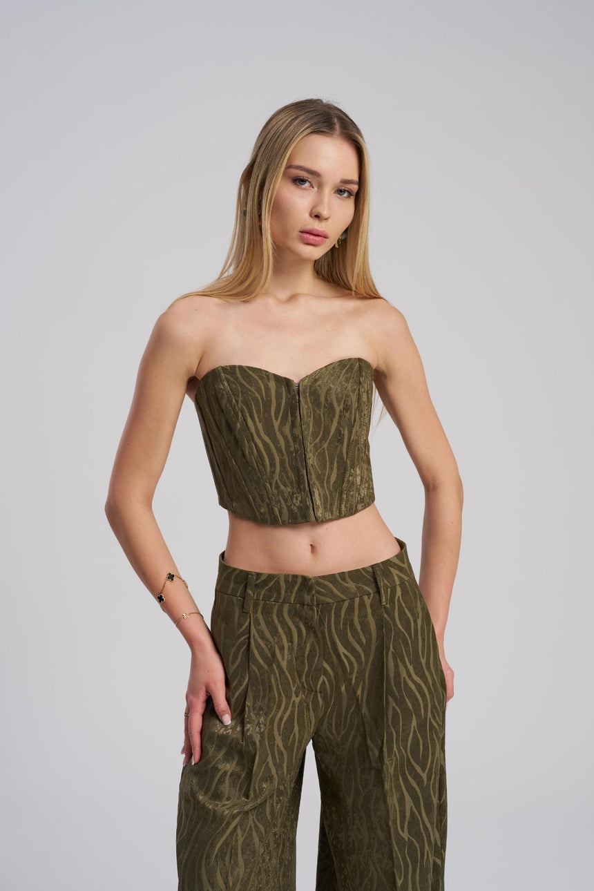 Woman wearing a green patterned strapless top and pants on a gray background