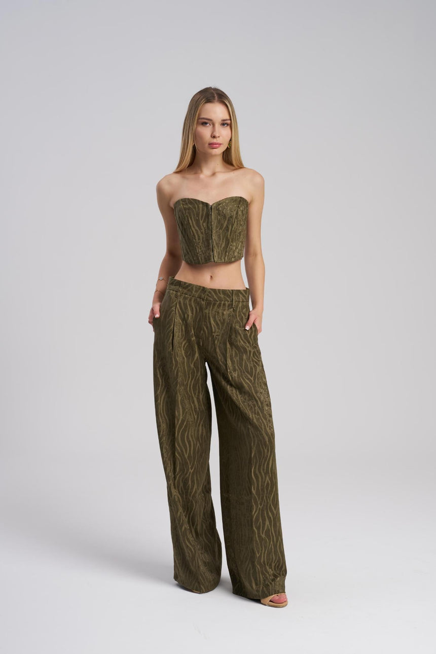 Woman wearing a green strapless top and wide-leg pants on a white background