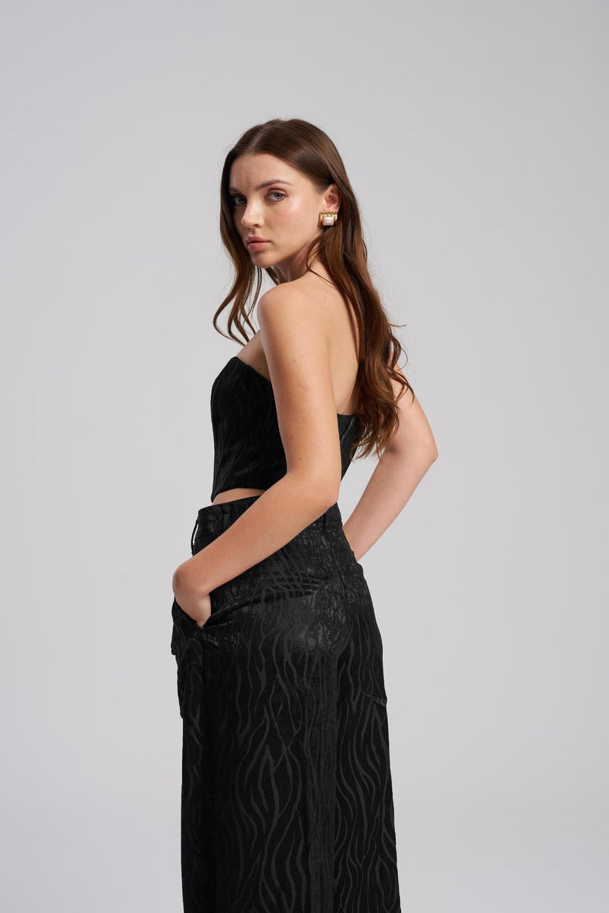 Woman wearing a black outfit with a textured pattern on a gray background