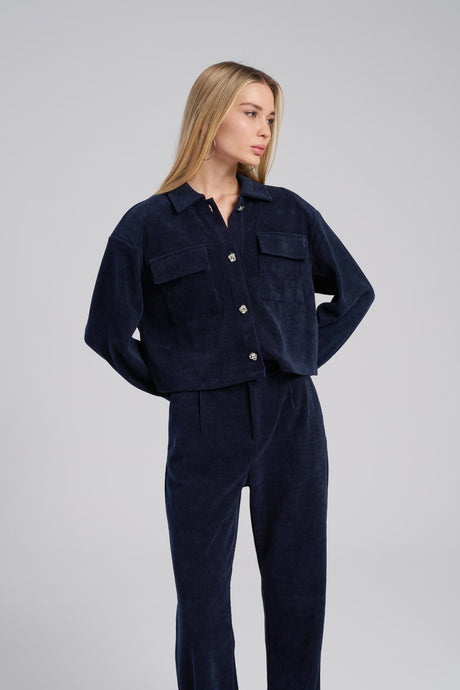 Woman wearing a navy blue corduroy outfit on a gray background