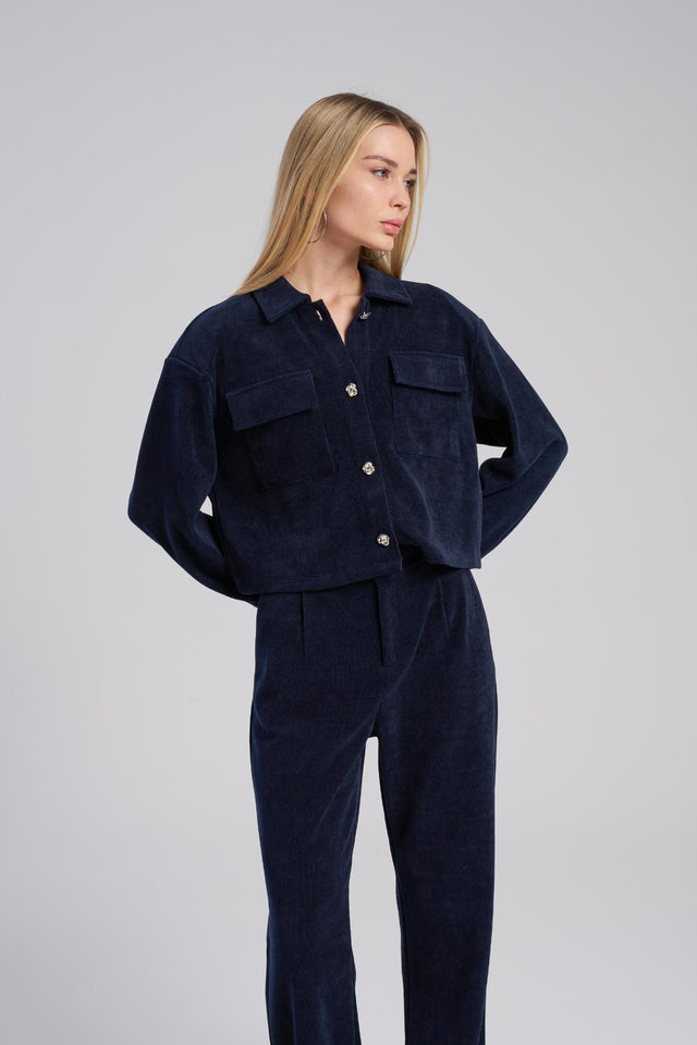 Woman wearing a navy blue corduroy outfit on a gray background