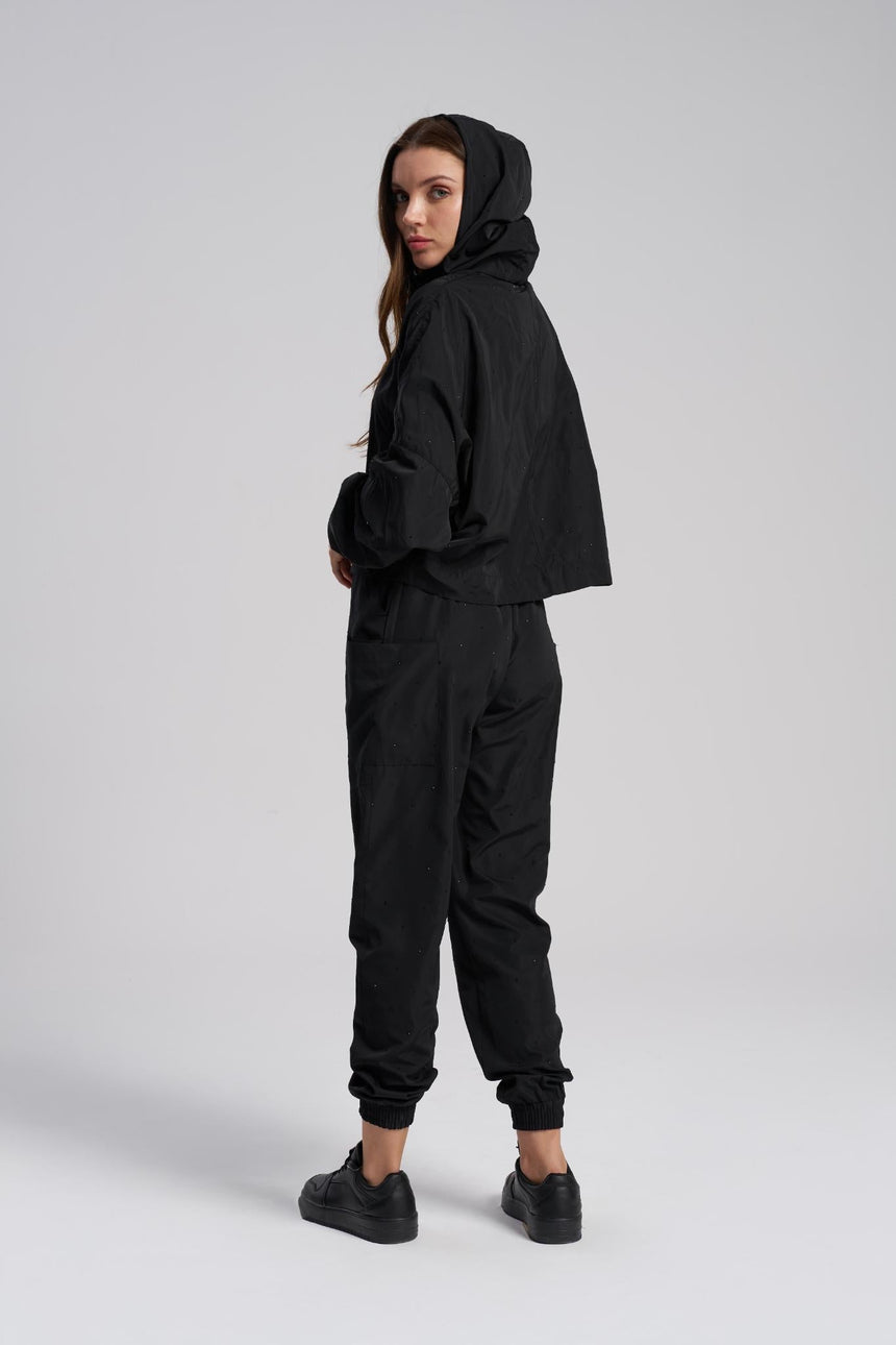 Person wearing a black hoodie and pants on a white background