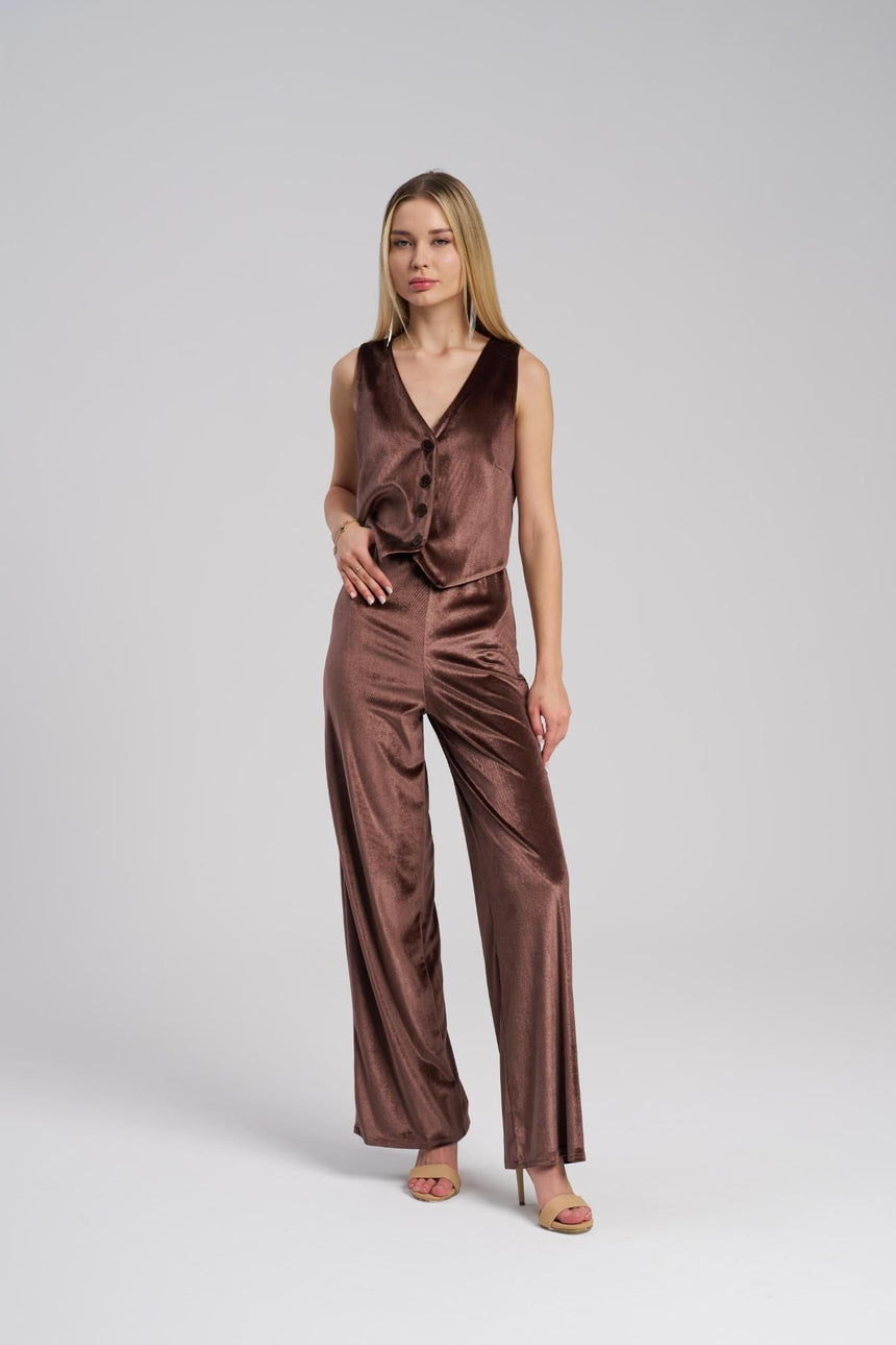 Woman wearing a brow velvet vest and pants on a white background