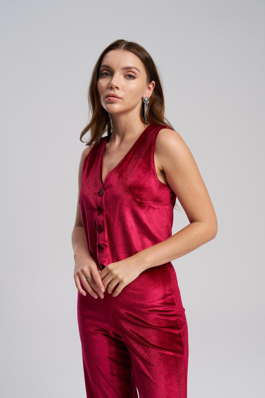 Woman wearing a red sleeveless top and pants on a gray background