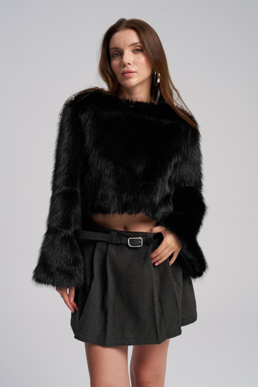Woman wearing a black fur coat and black skirt on a gray background